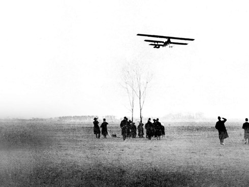 Sort/hvid billede af mennesker der kigger på fly i 1916
