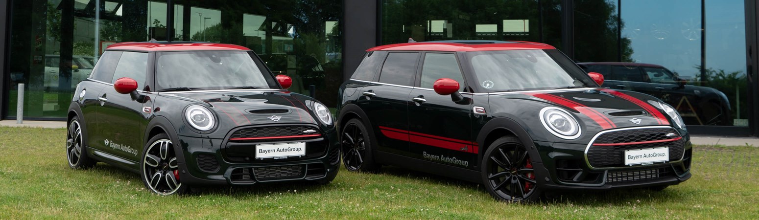 To MINI Coopers parkeret på græsplane foran Bayern AutoGroup forhandler