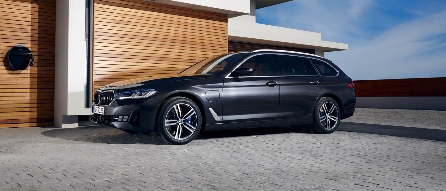 Sort BMW 5-serie Touring Plug-in Hybrid parkeret i indkørsel