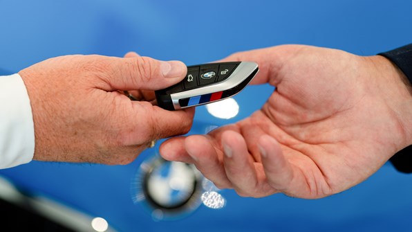 BMW bilnøgle som afleveres i en hånd